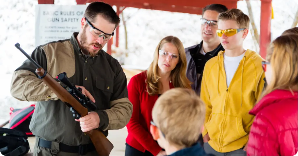 A firearms instructor demonstrates proper shooting techniques to a class of attentive students in a controlled environment.